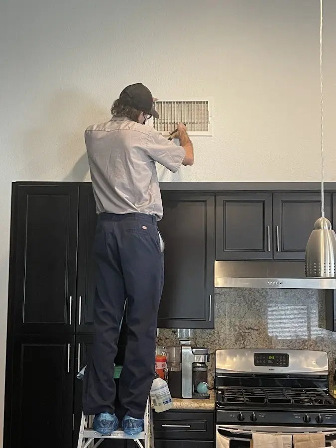 Technician inspecting an air vent during HVAC service in Shawnee